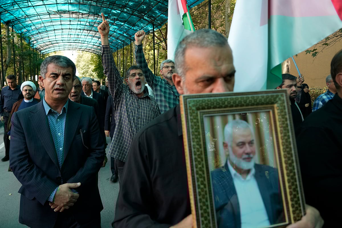 AP : Members of Tehran University Council chant slogans in a protest to condemn the killing of Hamas political chief Ismail Haniyeh, seen in the picture, at the University, in Tehran, Iran, Wednesday, July 31, 2024.